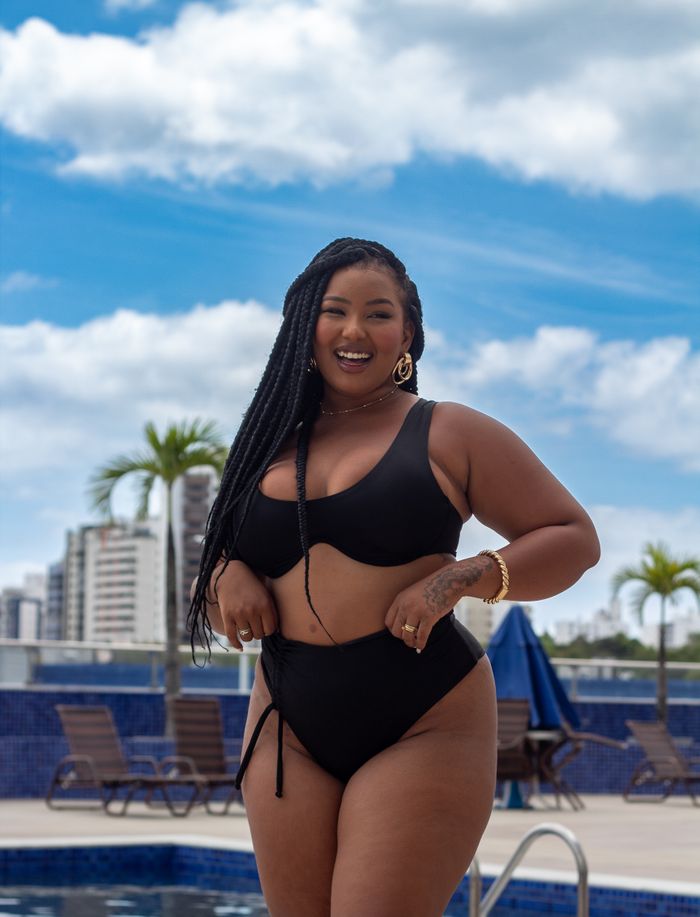 gallery-4 Smiling woman in a bikini enjoying summer by a pool with city skyline background.